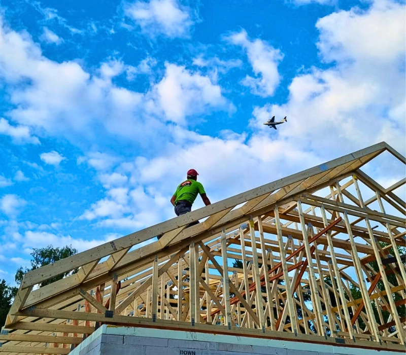 Jumiķis stāv uz kopņu jumta konstrukcijām un skatās debesīs uz lidmašīnu. Gan jumts, gan lidmašīna ir inženieru darba rezultāts un sargā cilvēku no stihijas spēkiem.